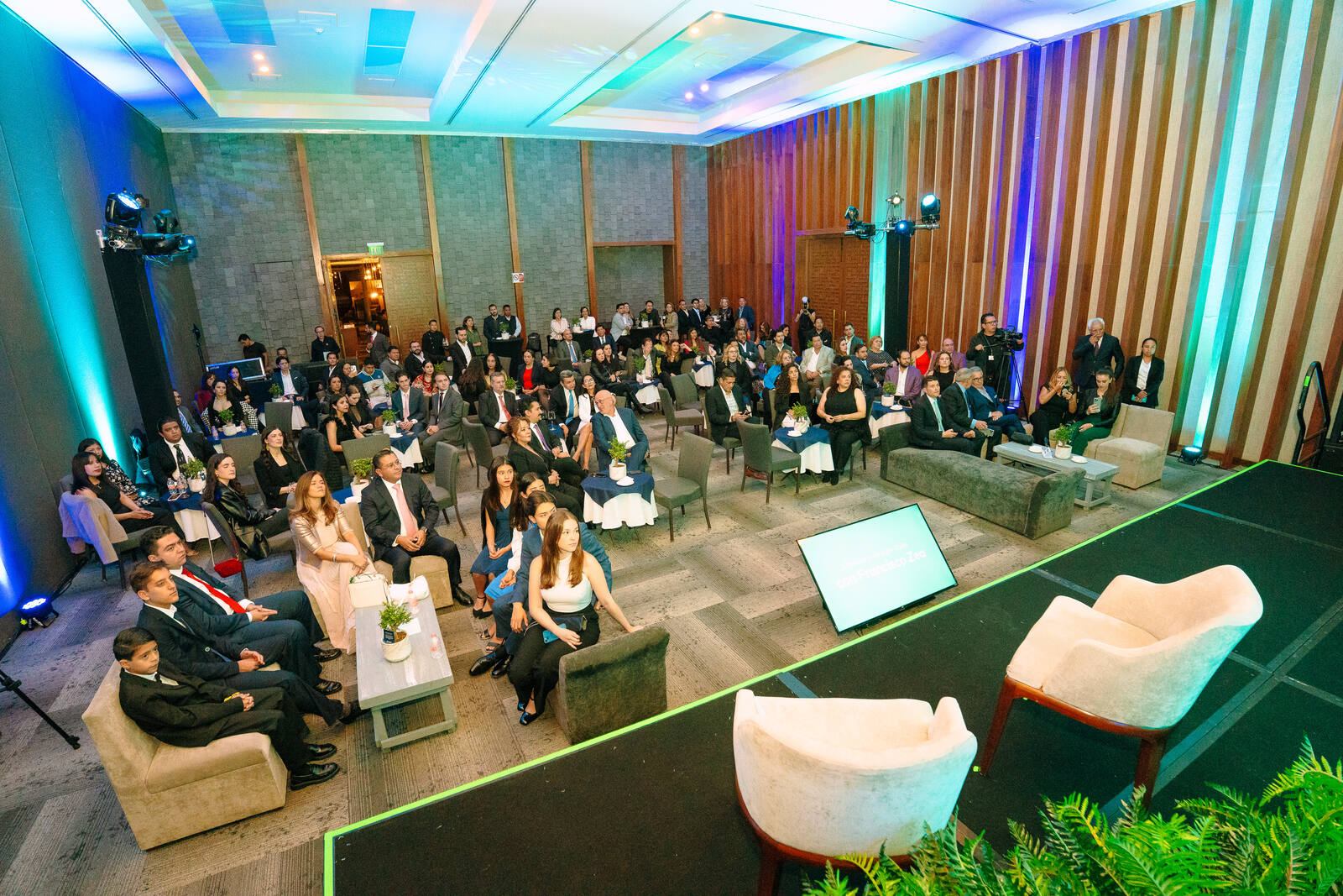 Salón de evento corporativo con audiencia y escenario