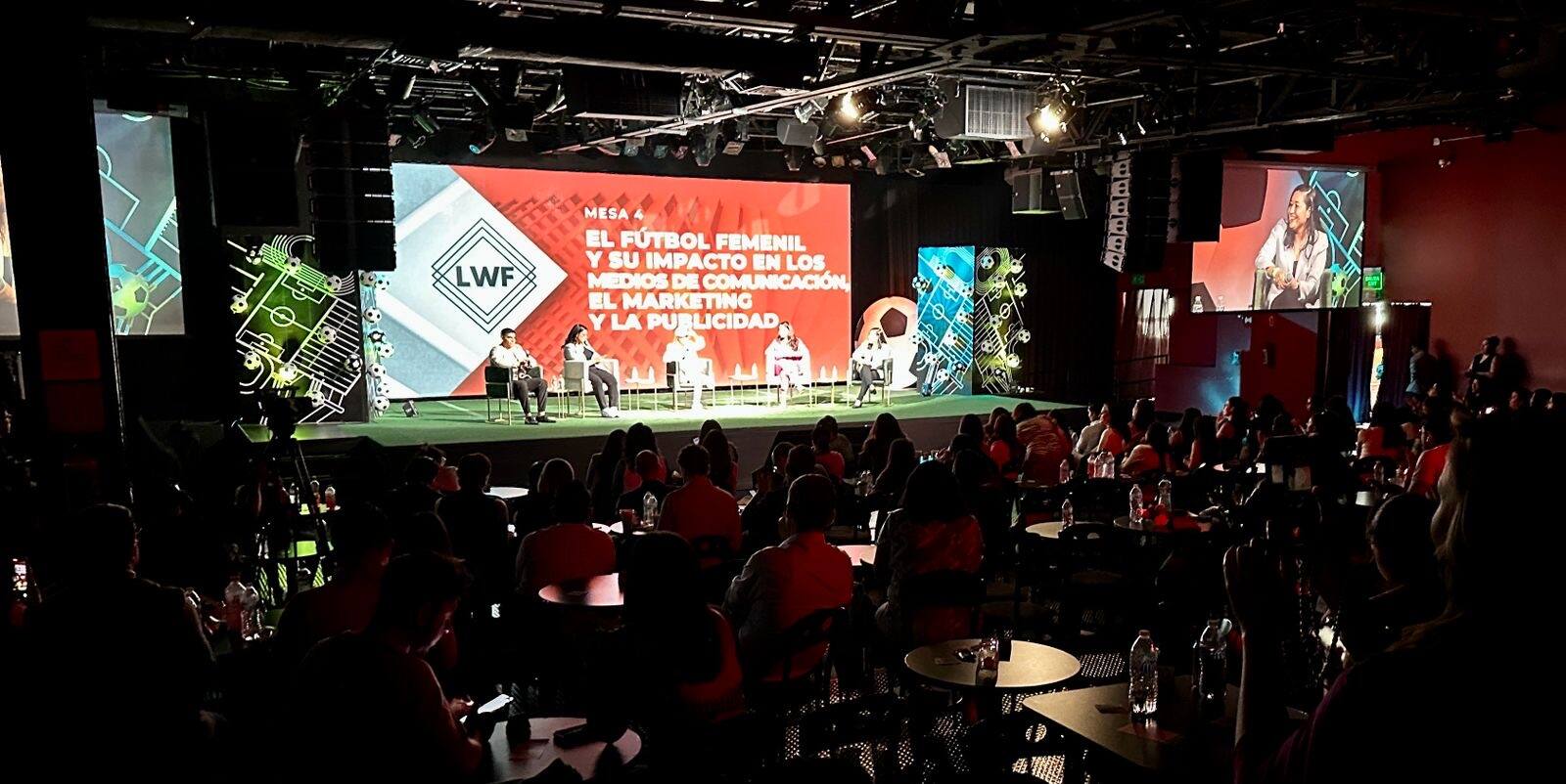 Audiencia frente a una mesa de conversación en escenario